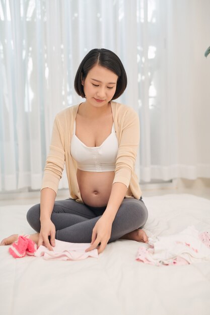 Foto felice futura madre che tiene in mano carino bodywear per neonato