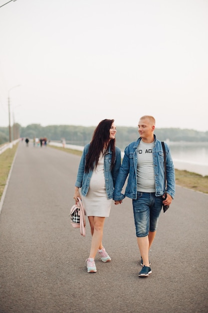 Happy future parent walking together in fresh air looking at each other and laughing Pregnant woman with husband expecting baby relaxing and spending free time together Concept of pregnancy