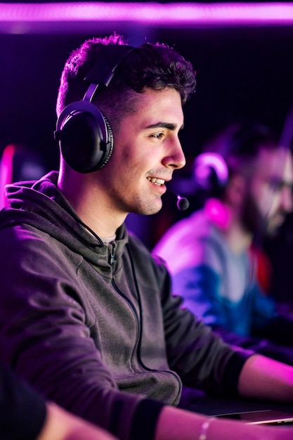 Happy gamer with headset playing video game online while sitting in gaming room