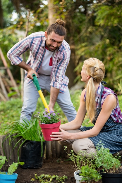 Happy gardeners planting potted plants at garden