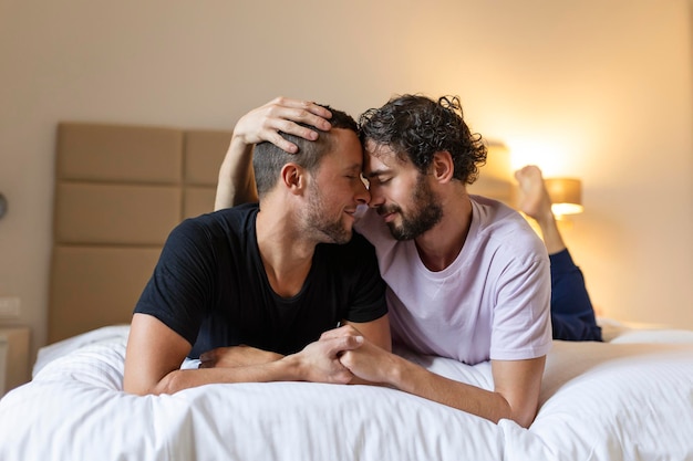 Happy gay couple lying down on the bed at home hugging and flirting LGBT gay couple love moments happiness concept