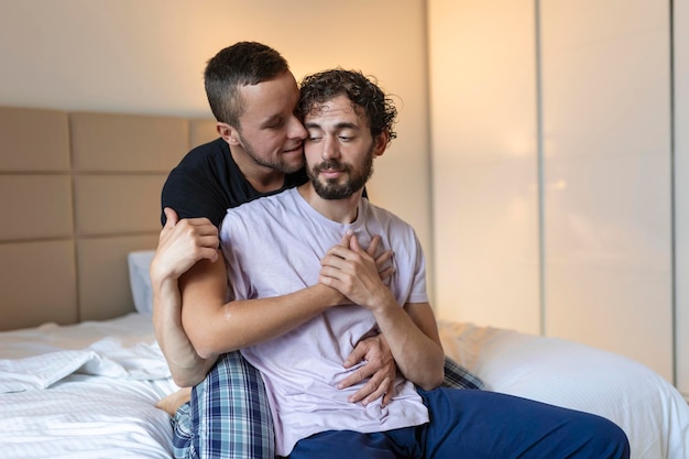 Happy gay couple lying down on the bed at home hugging and flirting LGBT gay couple love moments happiness concept