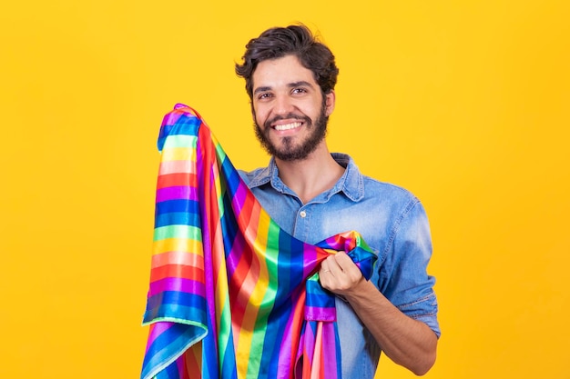 Uomo gay felice che si diverte a tenere la bandiera arcobaleno simbolo della comunità lgbtq