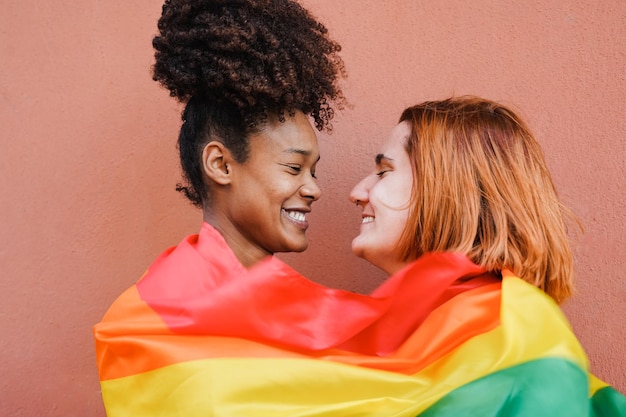 사진 프라이드 퍼레이드에서 lgbt 리안보우 깃발을 착용하면서 부드러운 순간을 보내는 행복한 게이 여성 커플