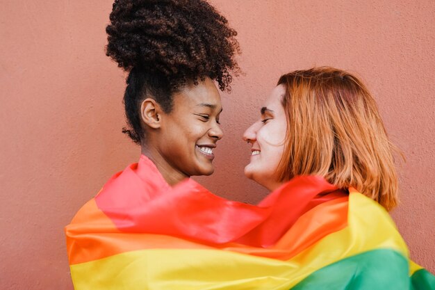 プライド パレードで LGBT rianbow フラグを身に着けている間、優しい瞬間を持つ幸せなゲイの女性カップル
