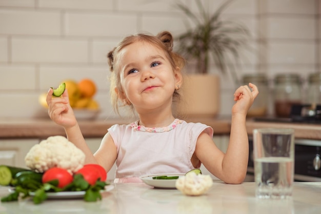 A happy girl 23 years old in the kitchen at home or in kindergarten eats delicious and healthy vegetables for lunch