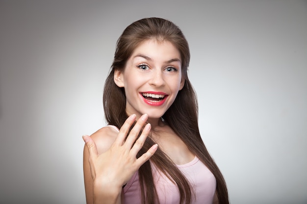 Happy girl after manicure session. Studio portrait on grey vignette background