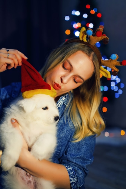 Photo happy girl in antler with samoyed husky dog in christmas decorations