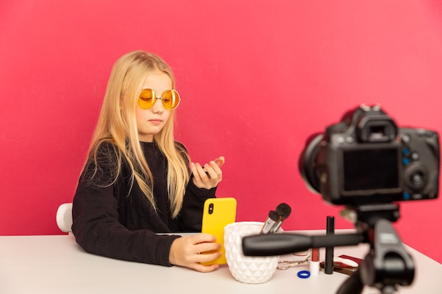 写真 vlogのためにカメラの前で話す自宅で幸せな女の子。ブロガーとして働いているティーンエイジャーは、インターネットのビデオチュートリアルを記録しています。