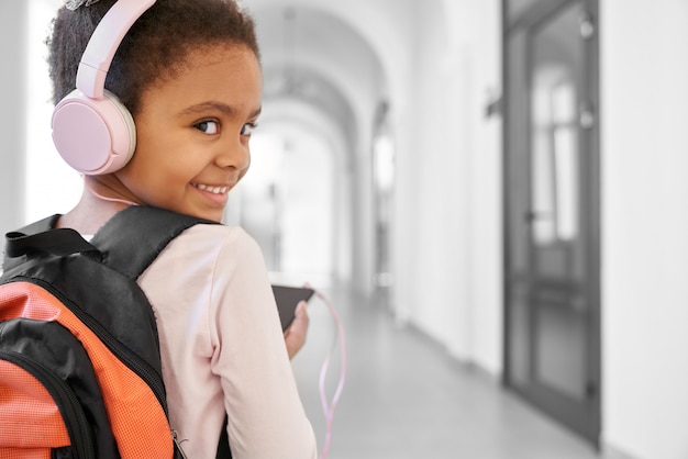 Happy girl in big pink headphones listening music