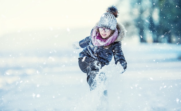 凍るような冬の公園や屋外で雪を吹く幸せな女の子女の子と冬の寒さ