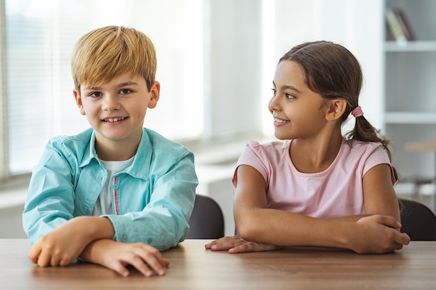 幸せな女の子とテーブルに座っている男の子