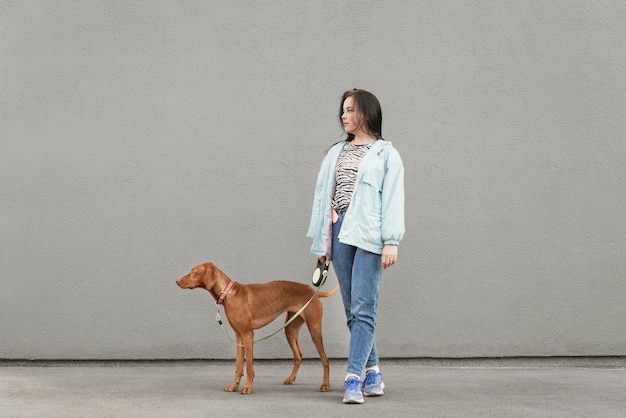 Happy girl and brown dog against a of gray walls.