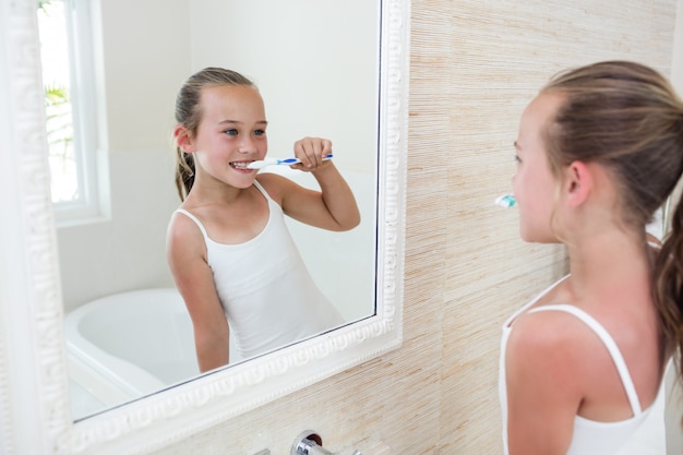 Happy girl brushing her teeth in bathroom