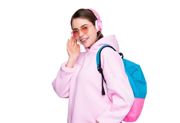 캐주얼한 분홍색 후드티를 입은 행복한 소녀는 배낭을 메고 헤드폰을 끼고 음악을 듣는 것을 즐깁니다.