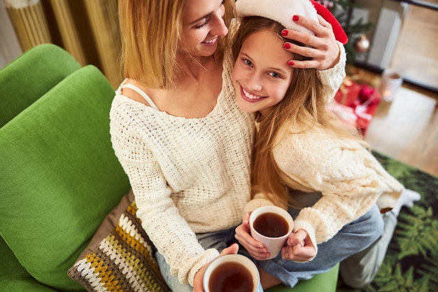 Happy girl celebrating Christmas with caring mother indoors