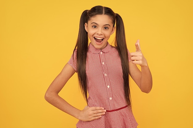 Happy girl child point finger gun hand gesture yellow background pointing