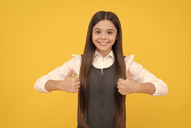 Happy girl child in school uniform smile showing double thumbs up hand gesture satisfaction