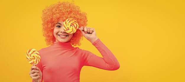 Happy girl child with orange hair in pink poloneck have fun holding lollipops girlhood funny teenager child on party poster banner header with copy space