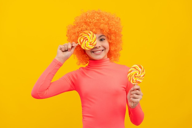 Happy girl child with orange hair in pink poloneck have fun holding lollipops, girlhood