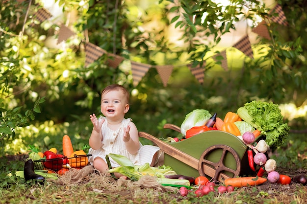 Happy girl cooks vegetable salad on the nature. A little gardener collects a crop of vegetables.