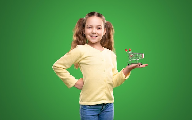 쇼핑 카트의 미니어처를 시연하는 행복한 소녀