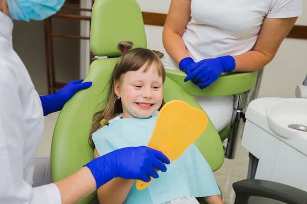 Ragazza felice al dentista guardarsi allo specchio