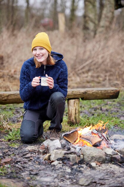 Happy girl drinking hot chocolate by bonfire