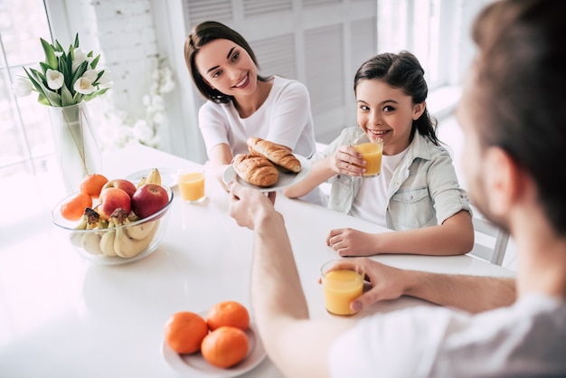 La ragazza felice che beve succo con i genitori