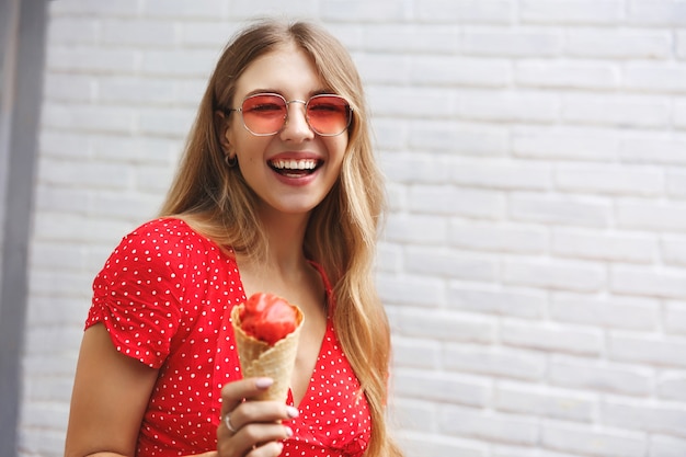 Happy girl eating ice cream on outdoor walk around city, smiling enjoying sweet street food 