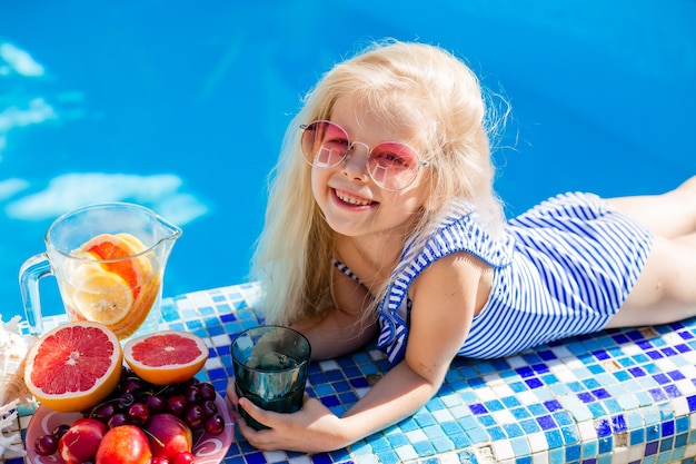행복 한 여자는 수영장에서 여름에 과일을 먹는