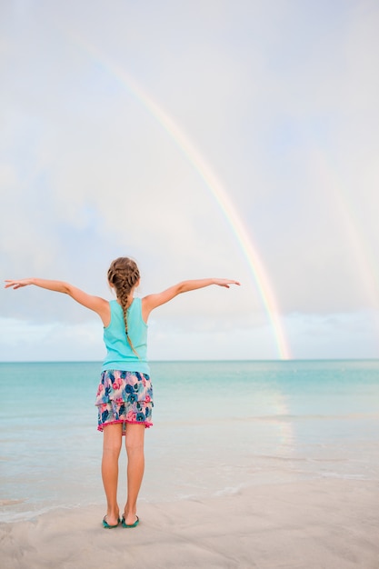 幸せな女の子は夏休みの背景、青い空と海の青緑色の水を楽しむ