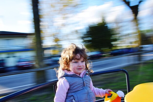 写真 遊び場でカルーセルを楽しんでいる幸せな女の子