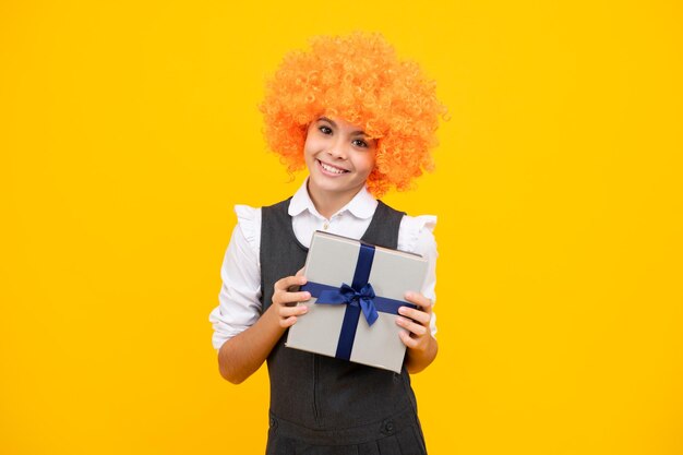 Happy girl face positive and smiling emotions child with gift present box on isolated studio background gifting for kids birthday