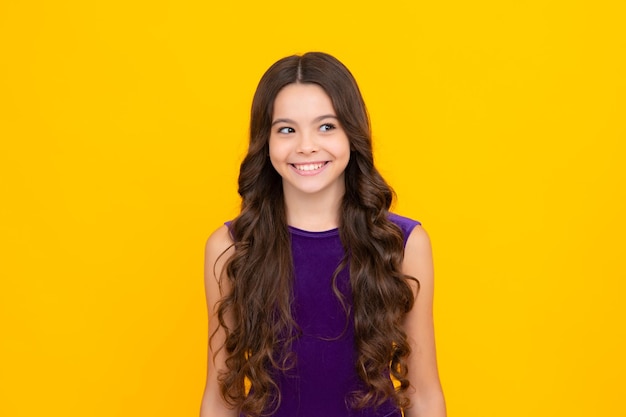 Happy girl face positive and smiling emotions Children studio portrait on yellow background Childhood lifestyle concept Cute teenage girl face close up