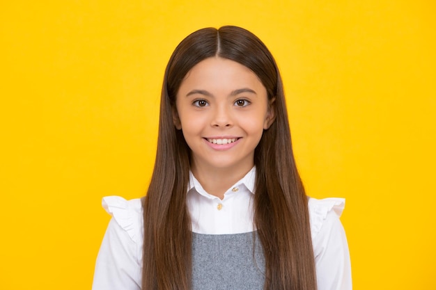 Happy girl face positive and smiling emotions Close up portrait of caucasian teen girl Head shot of cute teenager child on yellow isolated studio background