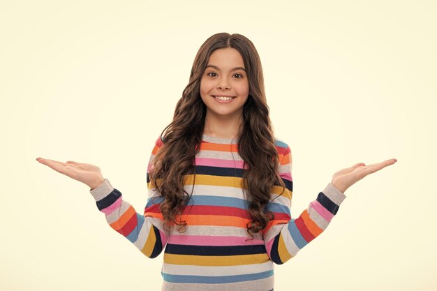 Happy girl face positive and smiling emotions portrait of cute teenager child girl pointing hand showing adverts with copy space over white background