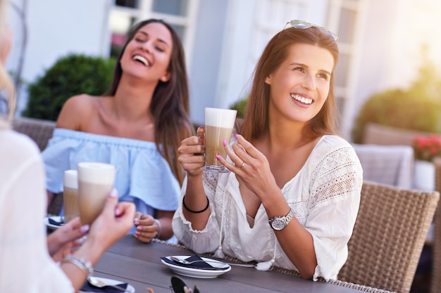 happy girl friends in cafe during summer time