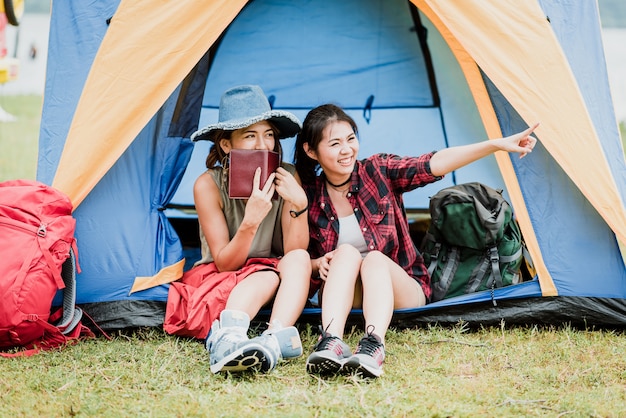 Photo happy girl friends in front of tent during camping