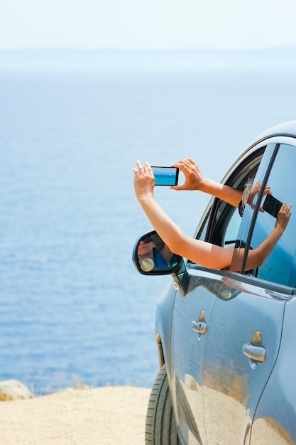 Foto una ragazza felice dall'auto in mare sullo sfondo della grecia