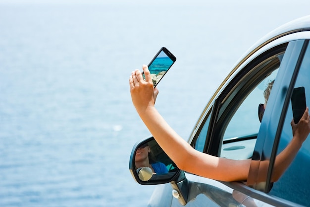 Счастливая девушка из машины на фоне моря греции
