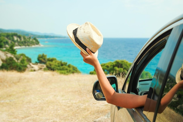 海のギリシャの背景で車から幸せな女の子