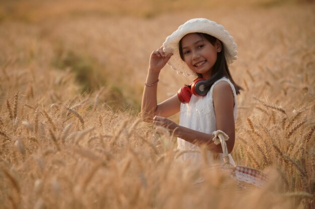 Happy girl in golden wheat field evening sunset on summer vacation