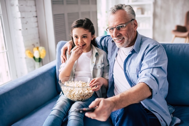 幸せな女の子とポップコーンでテレビを振る祖父