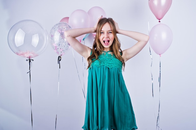 Happy girl in green turqoise dress with colored balloons isolated on white Celebrating birthday theme