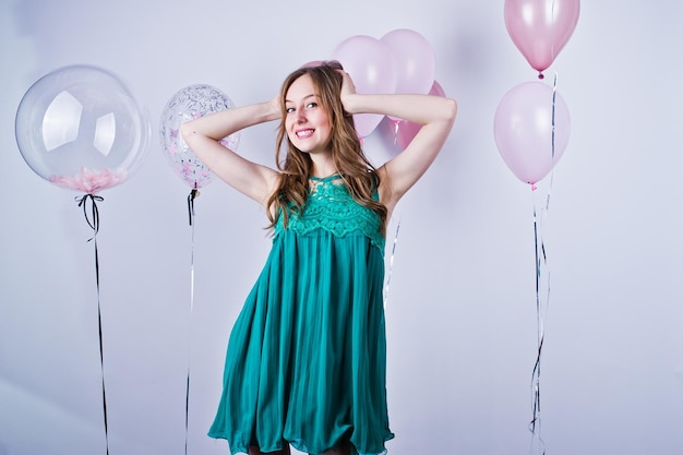 Happy girl in green turqoise dress with colored balloons isolated on white Celebrating birthday theme