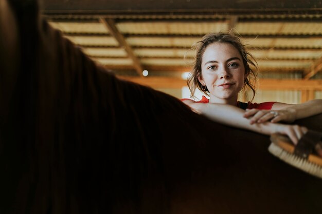 Happy girl grooming a chestnut horse