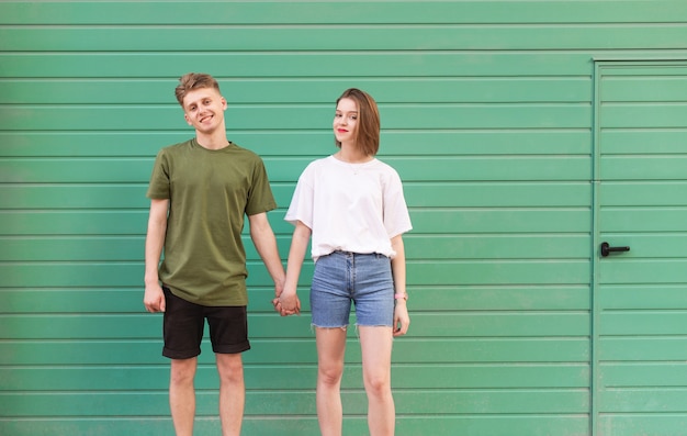 Happy girl and guy are isolated on the background of a green wall