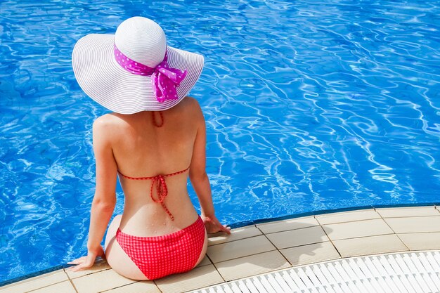 Happy girl in a hat by the pool at sea