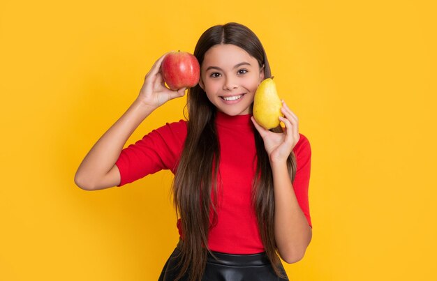 Happy girl hold fresh apple and pear on yellow background